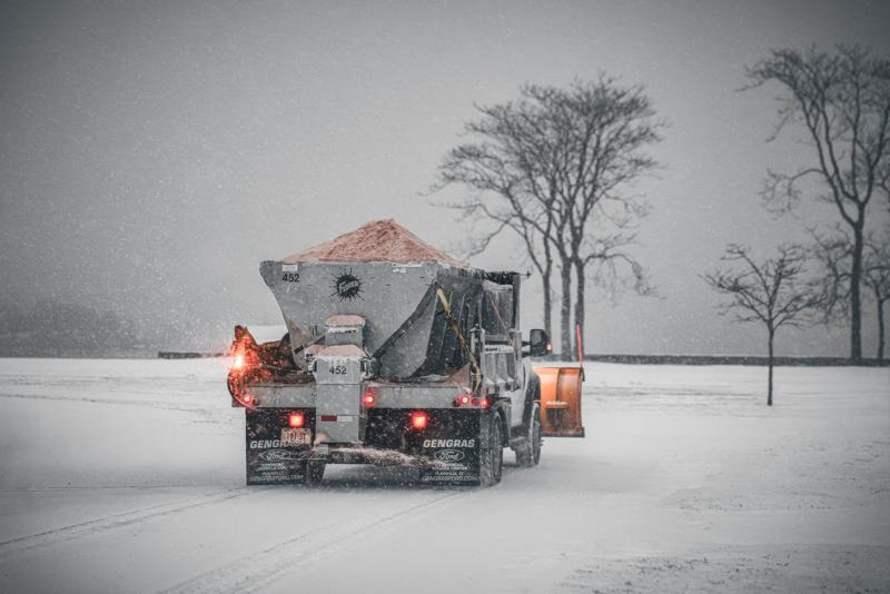 Truck spreading salt on a snowy road during a winter storm